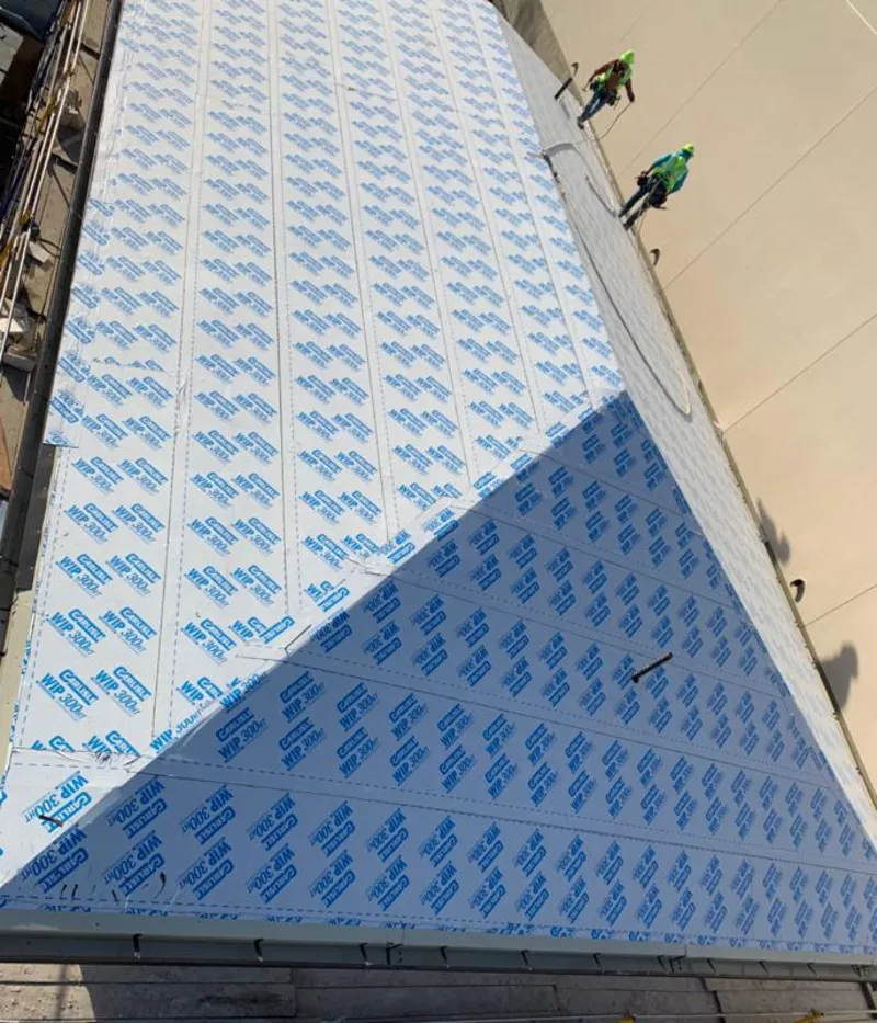 Professional roofers installing underlayment on a metal roof in Isanti